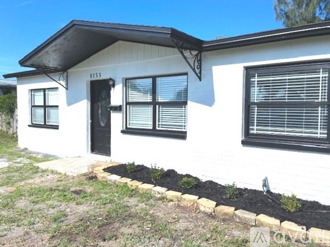 A white house with black shutters and a black door.