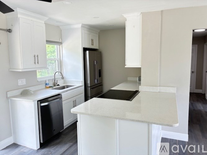 A kitchen with white cabinets and a black fridge.