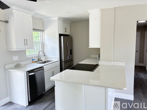 A kitchen with white cabinets and a black fridge.