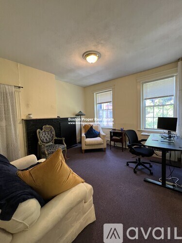 A living room with a couch, chairs, and a desk.