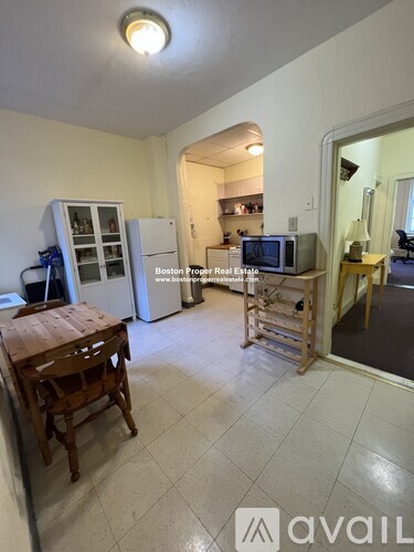 A kitchen area with a refrigerator, a microwave, and a wooden table.