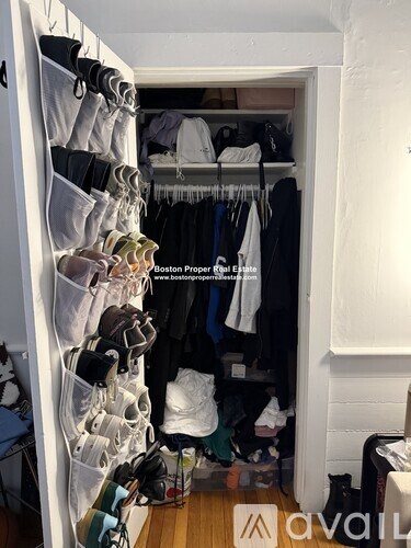 A white closet with clothes hanging on hangers.