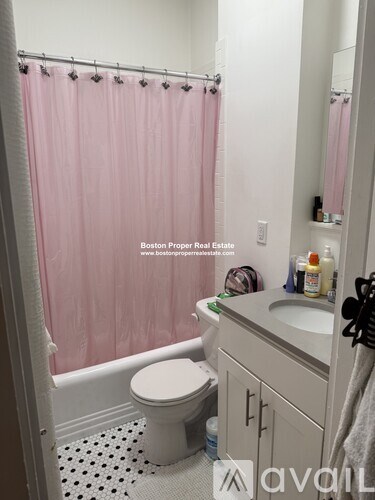 A bathroom with a pink shower curtain and a white toilet.