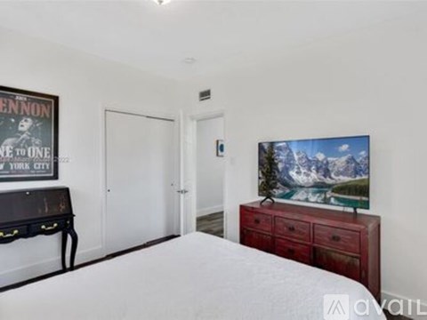 A bedroom with a bed, a dresser, and a poster on the wall.