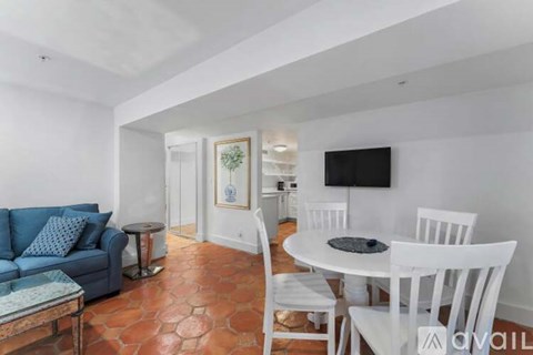 A living room with a blue couch and a white dining table.