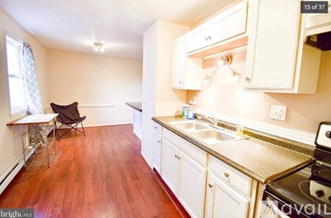 A kitchen with white cabinets and a wooden floor.
