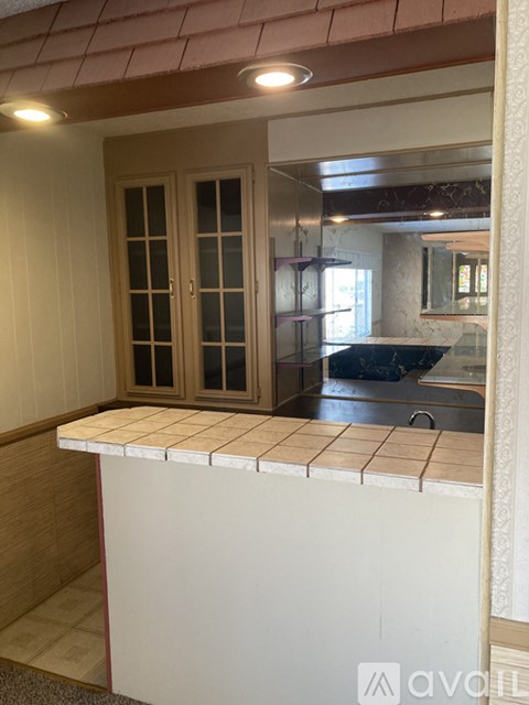 A kitchen with a white counter and wooden cabinets.