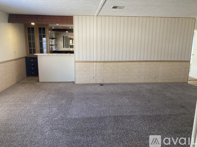 A room with a carpeted floor and a white cabinet.