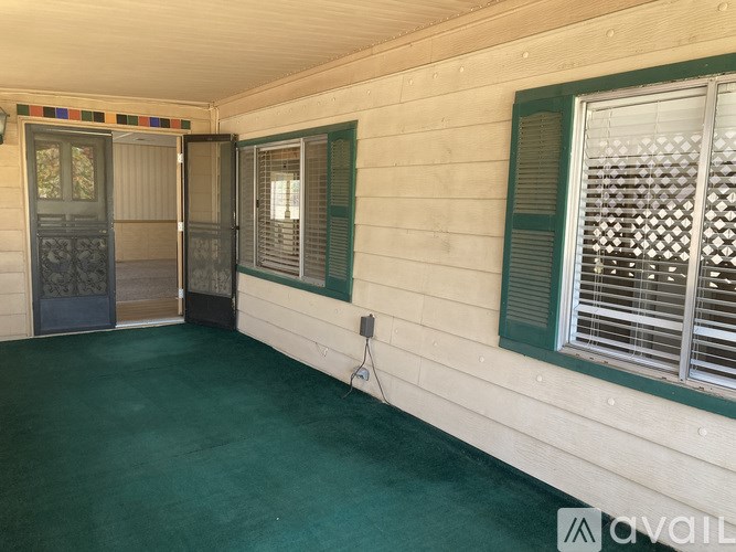 A room with a green floor and a window with green shutters.