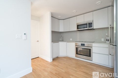 A kitchen with white cabinets and appliances, including a microwave and oven.