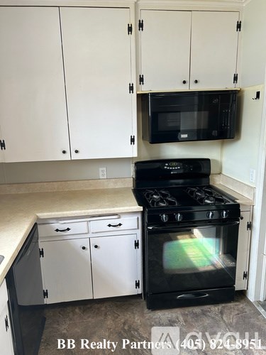 A kitchen with white cabinets and a black stove top oven.