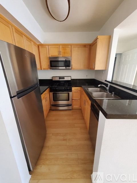 A kitchen with wooden cabinets and a stainless steel refrigerator.