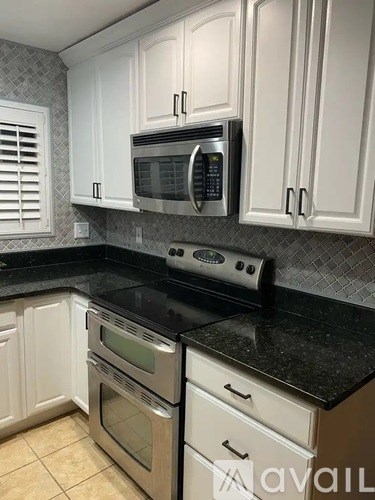 A kitchen with white cabinets and black countertops.