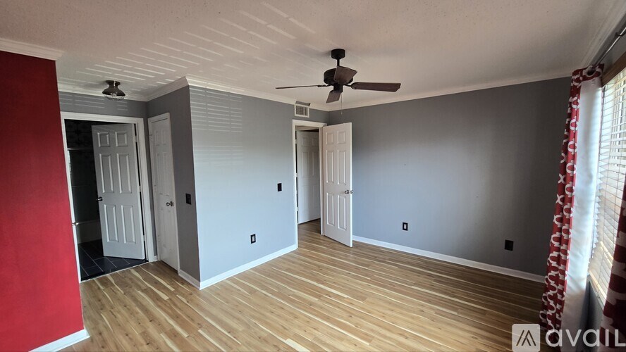 A room with a ceiling fan and wooden flooring.