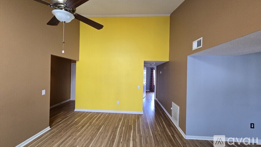 A room with a ceiling fan and wooden flooring.