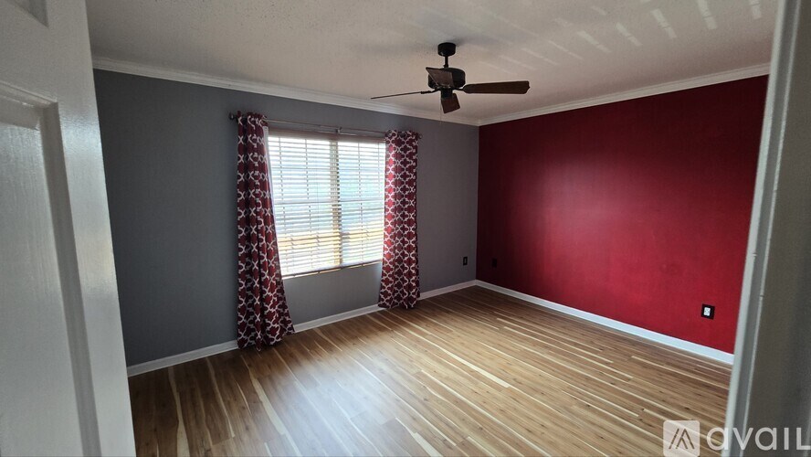 A room with a ceiling fan and a window with curtains.