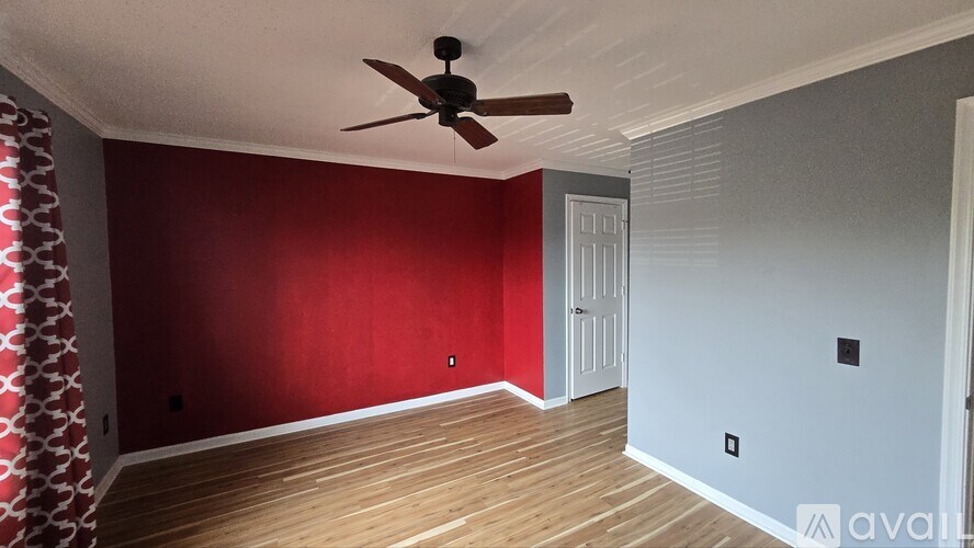 A room with a ceiling fan and wooden flooring.