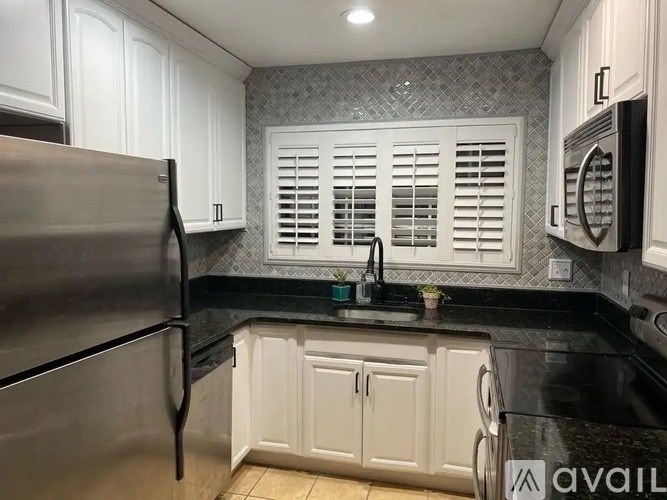 A kitchen with white cabinets and a black countertop.