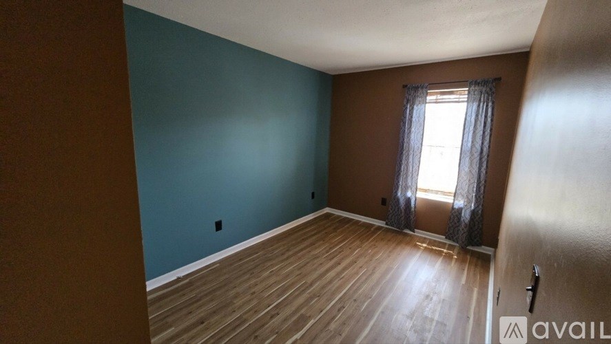 A room with wooden floors and a window with curtains.