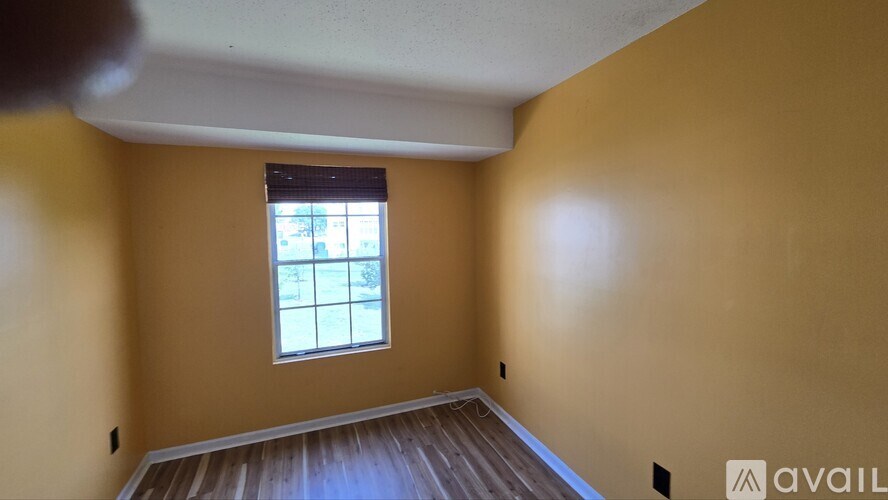 A room with a window and wooden flooring is available for rent.