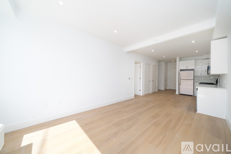 A spacious room with wooden flooring and white walls.