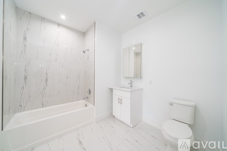 A white bathroom with a marble wall and a tub.
