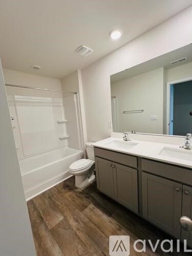 A bathroom with a toilet, sink, and mirror.