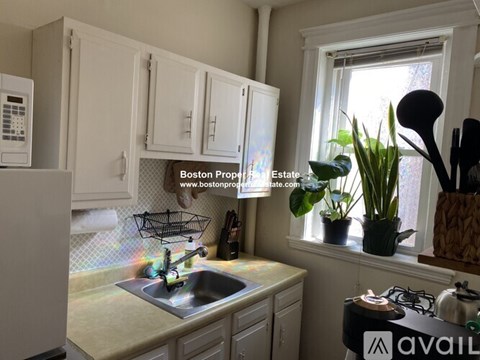 A kitchen with white cabinets and a window.