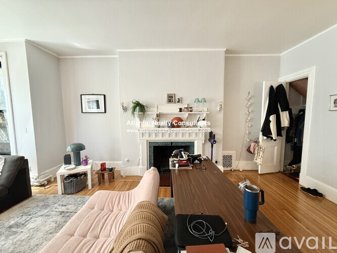 A living room with a grey couch, a wooden coffee table, and a desk with a computer.