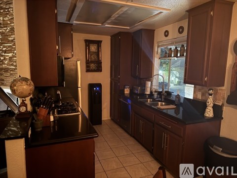 A kitchen with dark brown cabinets and a black countertop.