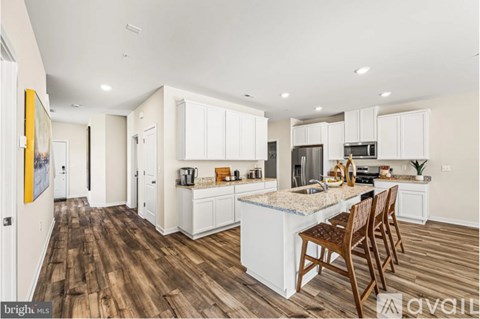 A kitchen with white cabinets and a wooden floor.