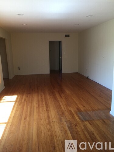 A room with wooden flooring and a door in the background.