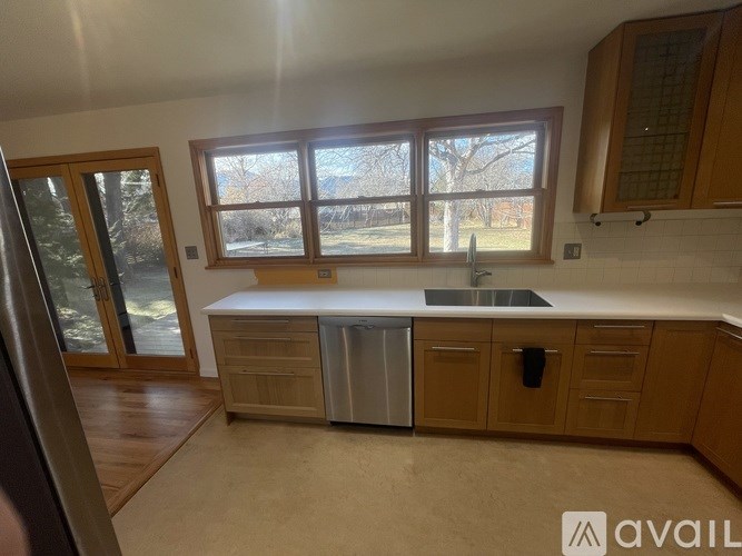 A kitchen with wooden cabinets and a window overlooking a tree.