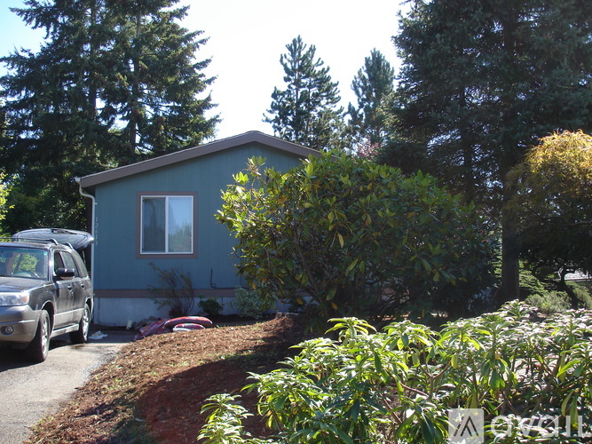 A blue house with a silver car parked in front.