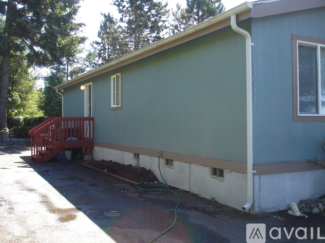 A house with a green and blue exterior has a red staircase outside.