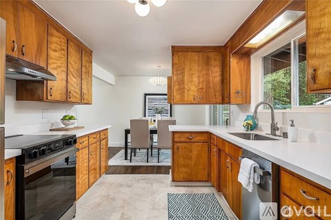 A kitchen with wooden cabinets and a black and white rug on the floor.