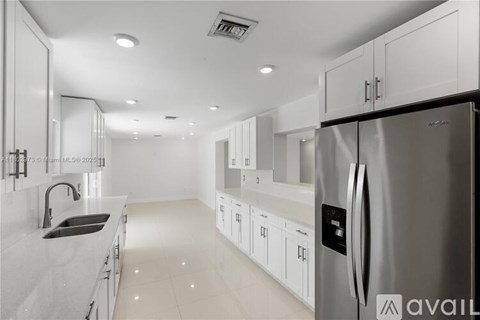A modern kitchen with white cabinets and a stainless steel refrigerator.