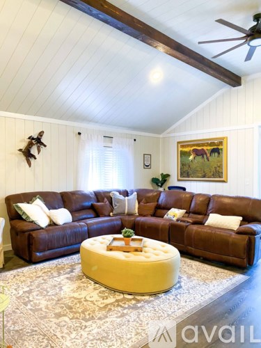 A living room with a brown leather couch and a coffee table in the center.