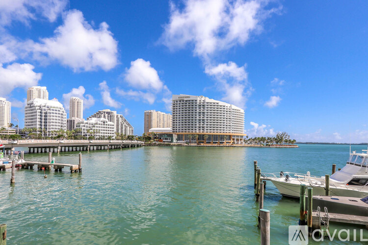 A city skyline is seen from the water with boats docked in the foreground.