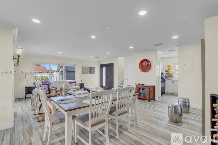 A dining room with a table set for six with white chairs.