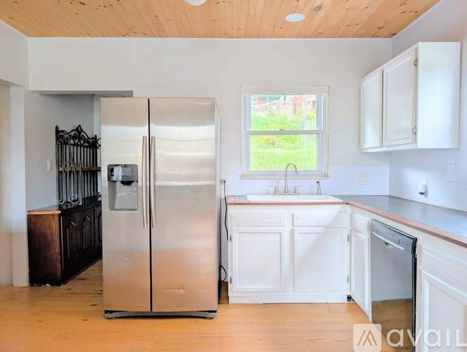 A kitchen with a stainless steel refrigerator and white cabinets.