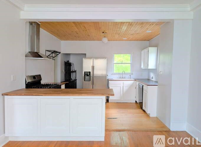 A kitchen with white cabinets and a wooden ceiling.