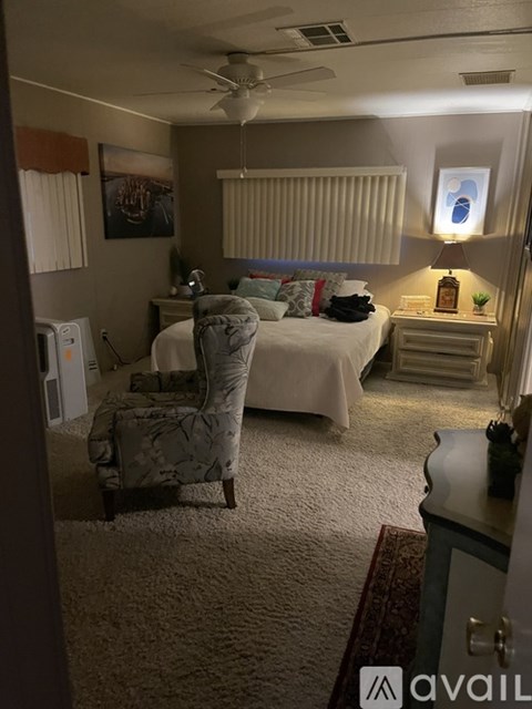 A bedroom with a bed, chair, and a ceiling fan.