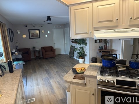 A kitchen with a stove top oven and a dining area with chairs.