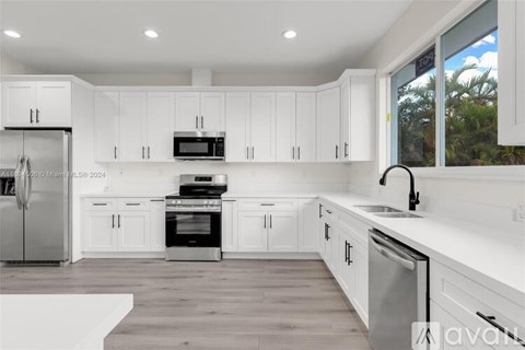 A modern kitchen with white cabinets and stainless steel appliances.