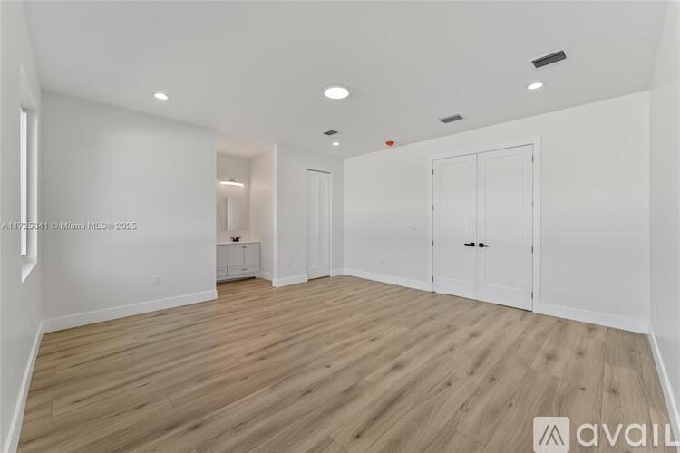 A spacious room with wooden flooring and white walls.