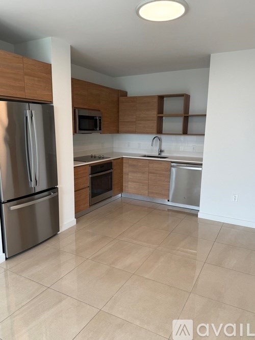 A kitchen with a refrigerator, microwave, oven, and sink.