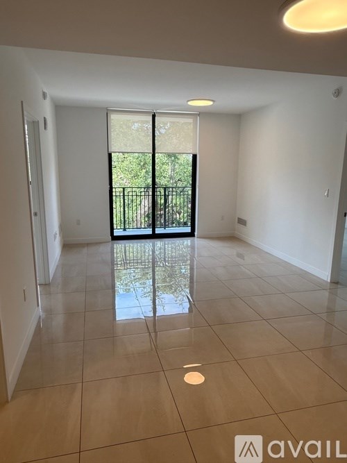 A spacious room with tiled flooring and a sliding glass door leading to a backyard.