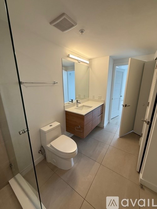 A bathroom with a toilet, sink, and mirror.