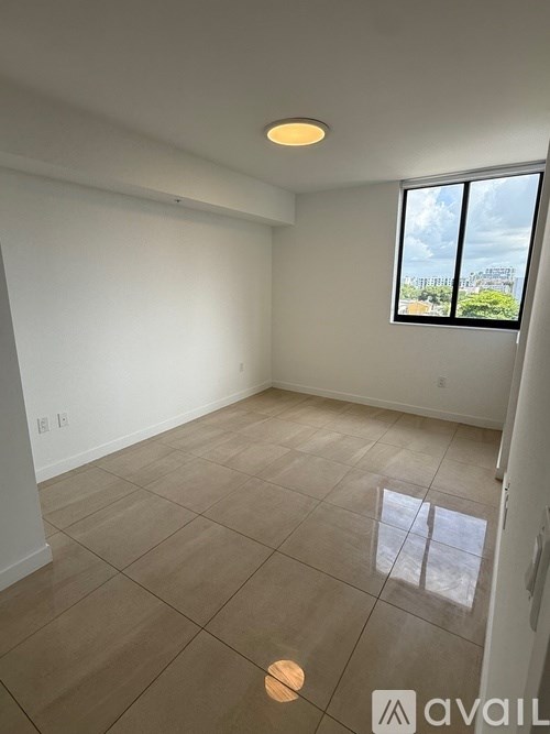 A room with a large window and tiled flooring.